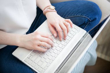 Bir aletle çalışan genç bir kızın elleri. Dizüstü bilgisayarda çalışıyor. Parlak renkler.