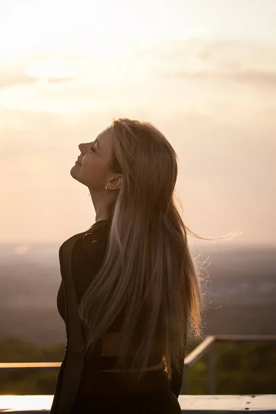 young blonde woman enjoys life in the rays of the sunset