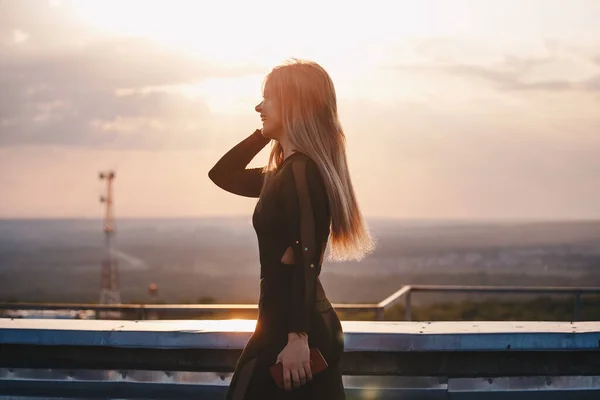 young blonde woman enjoys life in the rays of the sunset