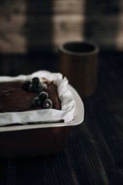 Kahverengi bir küfte donmuş kuşüzümü ve koyu arkaplanda beyaz parşömenle süslenmiş kek.