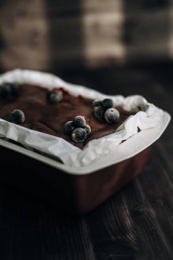 Kahverengi bir küfte donmuş kuşüzümü ve koyu arkaplanda beyaz parşömenle süslenmiş kek.