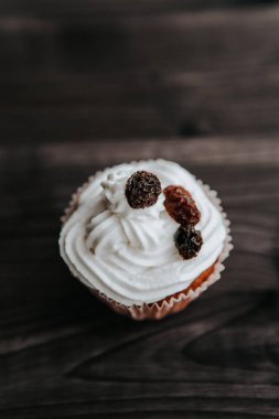Koyu ahşap arka planda kremalı ve kuru üzümlü kek.