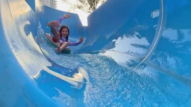 Su parkında kayan çocuk eğlenceli bir yaz aktivitesi yapıyor. Dışarıda ailesiyle eğlenceli bir tatil anısı yaratıyor.