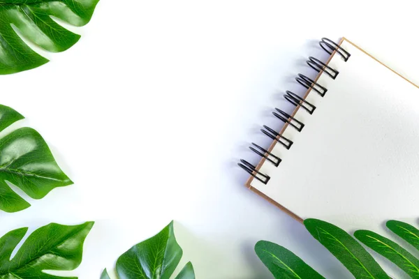 note book on white background decoration with green leaves, copy space