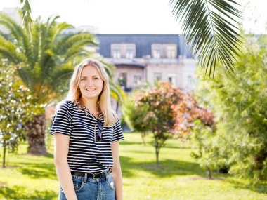 Etrafa, palmiye ağaçları ve park etmiş arabaların, güneşli ile tropikal şehrin sokakta parlak yaz günü yürüme çekici erkek genç güzel