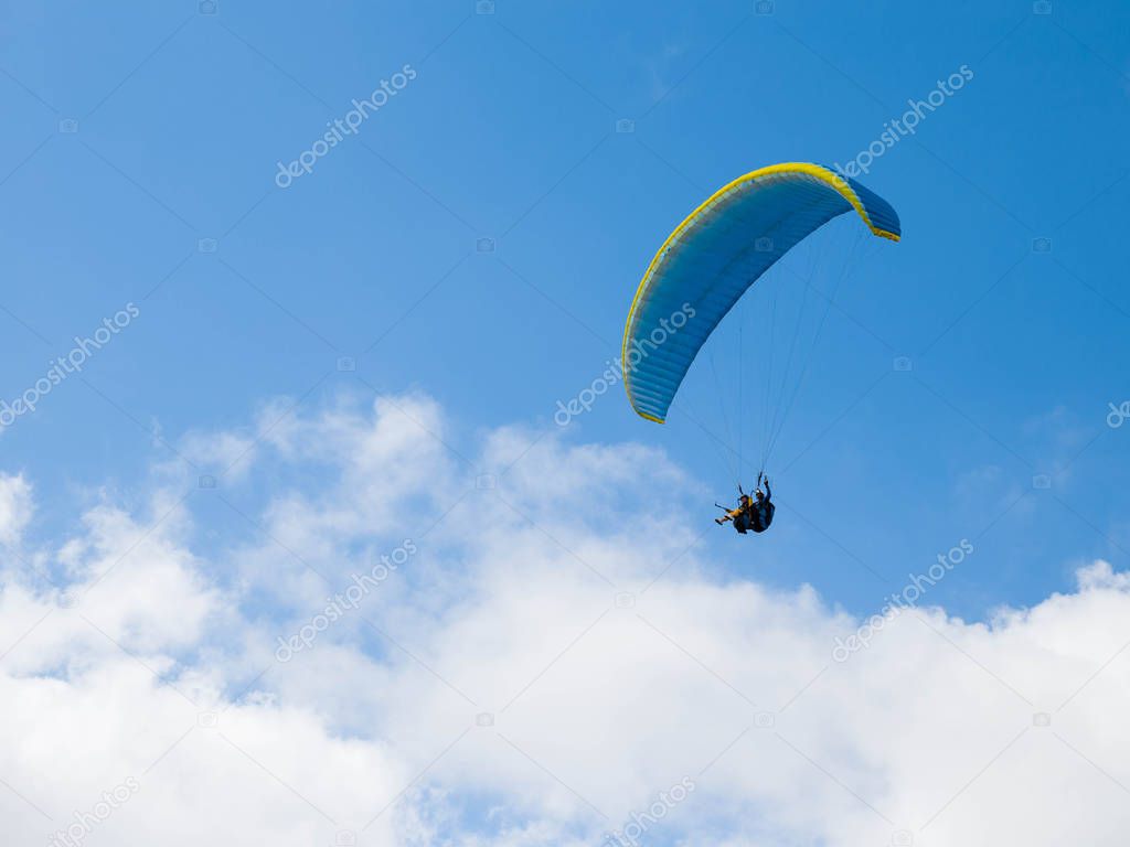 Paraglider final approach before landing, view against blue cloudy sky