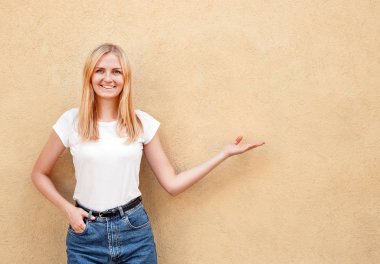 Hippi kız boş beyaz t-shirt ve jeans kadın el ile gösterir kaba sokak duvara, minimalist kentsel giyim tarzı, poz giyiyor