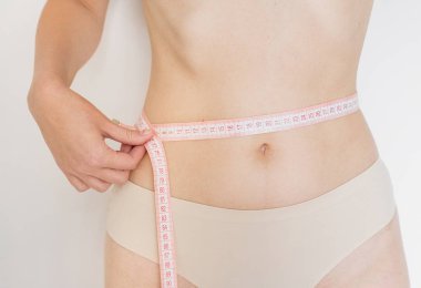 İnce genç kadın ince beline bir mezura, fitness ve diyet kavramı ile ölçme
