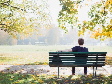 Genç adam geri ile rahatlatıcı bir sonbahar gününde park düşünme bakarak döndü