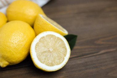 Bütün ve dilimlenmiş limon kahverengi ahşap zemin üzerinde. Organik taze narenciye, kopya alanı.