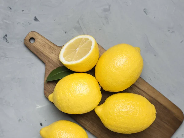 Цілі і нарізані лимони на дерев'яній обробній дошці. Органічні свіжі цитрусові, вид зверху, простір для копіювання . — стокове фото