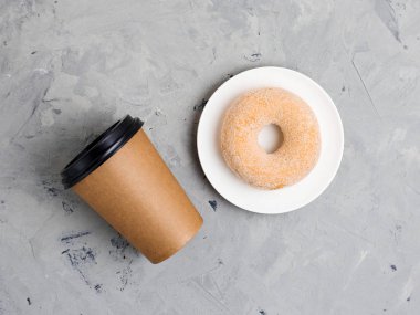 Gri beton arka plan üzerinde renkli şeker donut ve kahverengi kağıt fincan, yakın, üst görünümü. Fırın konsepti, taze hamur işleri, lezzetli kahvaltı, fast food