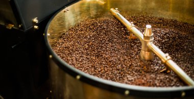 Kızartma makinesi. Soğutma silindirine dökülen bir kahve kavurma makinesinden taze kavrulmuş kahve çekirdekleri.