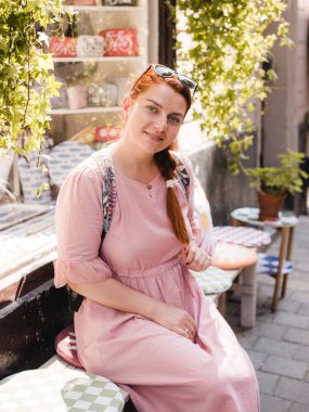 Bir kadın bir kafede sipariş bekliyor ve terasta oturur. Bir kahve molası daydreaming.