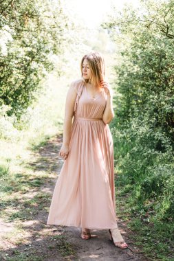 Ormandaki bir yolda duran zarif beyaz elbiseler giyen güzel genç bir kadın.