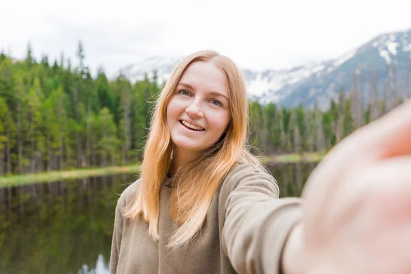 The girl tourist taking selfie in the mountain lake. Looking at camera and smile. Travel and active life concept. Outdoors — Stock Photo, Image