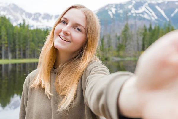 A turista lány szelfit készít a hegyi tóban. Nézz a kamerába és mosolyogj. Utazás és aktív élet koncepció. Szabadtéri — Stock Fotó
