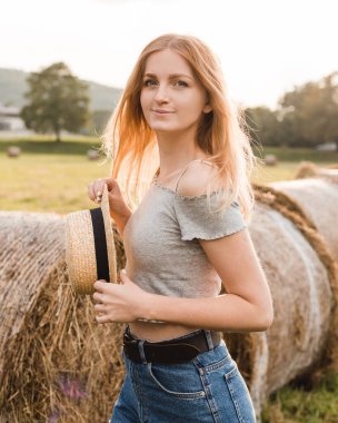 Yazın hasat edilen buğday tarlasında samanlıkta yuvarlanan seksi sarışın kız. Seçici odak.