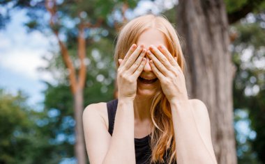 Gülümseyen ve gülen genç bir kadının kapalı bakışlı portresi. Duygusal yüz ifadesi. Doğa geçmişi.