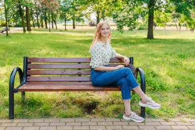 Güzel genç kadın bir bankta oturuyor.