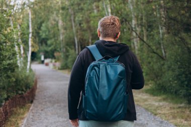 Sırt çantalı sarışın adam kırsalda dikiz aynasından görülüyor. Gezgin. Yaz zamanı. Açık havada dikilen, 30 'lu yaşlarda, sıradan giyinmiş genç bir adamın portresi.