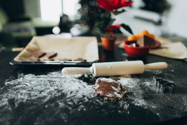 Noel kurabiyesi yapıyorum. Siyah masa üzerinde hamur ve malzeme içeren kompozisyon.