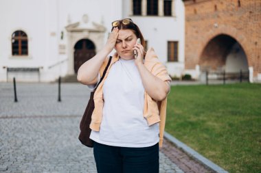 Başı ağrıyan 30 'lu yaşlardaki kızıl saçlı kadın dışarıdaki telefonları arıyor.