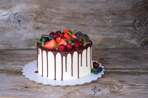 beyaz krem krem, güzel ev yapımı kek dekore kiraz, çilek ve yaban mersini, ahşap bir masa üzerinde