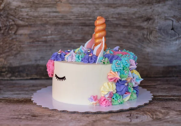 beautiful homemade cake in the form of a unicorn with cream colored flowers on a wooden table