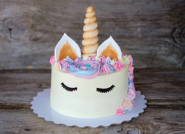 beautiful homemade cake in the form of a unicorn with cream colored flowers on a wooden table