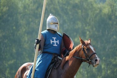 Ortaçağ knight bir binicilik alanında yeşil orman arka plan üzerinde bir mızrak ile. tarihi yeniden yapılanma