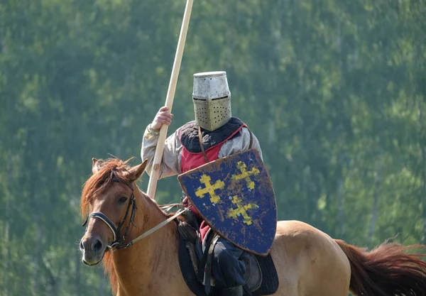 Ortaçağ knight bir binicilik alanında yeşil orman arka plan üzerinde bir mızrak ile. tarihi yeniden yapılanma