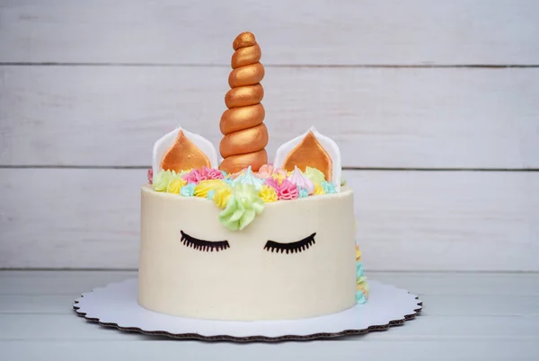 beautiful birthday cake in the shape of a unicorn on a white wooden background