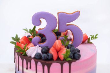 güzel Doğum günü pastası ile sayı 35, taze çilek ve yaban mersini ile dekore edilmiştir. Mor ve pembe peynir krem. Beyaz arka plan.