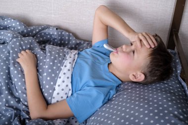 hasta çocuk çocuk yalan yatak ile bir termometre içinde ağız ve alnına dokunmak