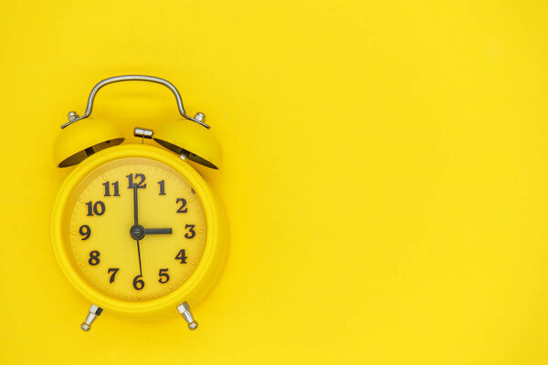 yellow vintage alarm clock with arrows and bell on yellow background. blank for design, space for text, time concept