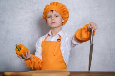 yakışıklı bir Turuncu elbiseli şefin kesme bıçağı turuncu biber