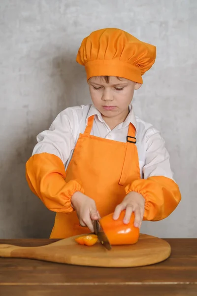 Lindo chico en un traje naranja cuchillo de cocina pimienta naranja — Foto de Stock