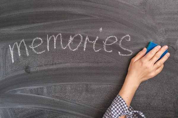 Το χέρι μιας γυναίκας σβήνει τις αναμνήσεις από την επιγραφή με κιμωλία σε ένα μαύρο Συμβούλιο. την έννοια της έναρξης μιας νέας ζωής, εγκαταλείποντας το παρελθόν — Φωτογραφία Αρχείου