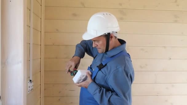 専門の電気技師は 新しい木造住宅に電気ソケットと配線のインストールを行います — ストック動画