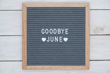 text in English goodbye June and a heart sign on a gray felt Board in a wooden frame clipart