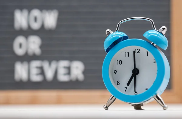 Blue analog alarm clock on Russian text background now or never. Концепция немедленных действий — стоковое фото