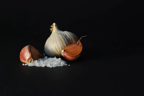 garlic and coarse salt on a black background