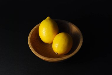 bir tabak doğal malzemelerin içinde siyah bir zemin üzerine limon meyve