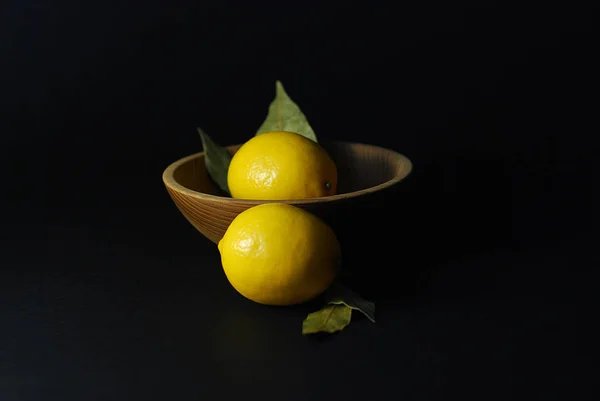 lemon fruits on a black background in a plate of natural material