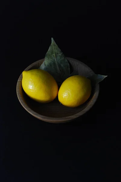 lemon fruits on a black background in a plate of natural material