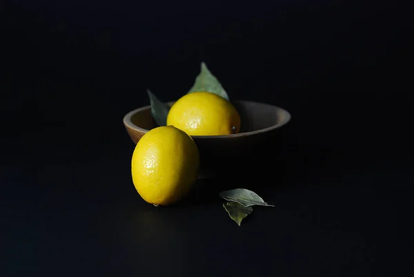 lemon fruits on a black background in a plate of natural material