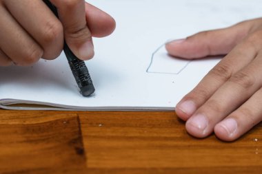 kids using a black rubber eraser to remove a pencil sketch on paper