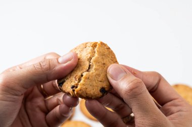 A close-up of two hands gently holding a golden brown cookie, ready to break it in half