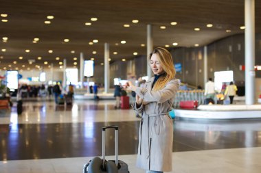 Kadın kişi valiz ve bakarak ile Havaalanı salonu gidiş.